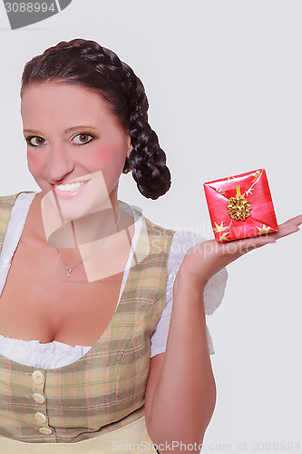 Image of Young Bavarian woman in dirndl with a small gift on your palm.