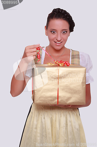 Image of Young woman in Bavarian Dirndl grabs a gift from