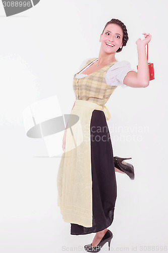 Image of Young Bavarian woman in dirndl holds a small packet with a finger over the shoulder