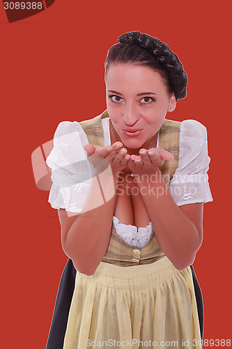 Image of Young Bavarian woman in dirndl breathed on palms of your hands