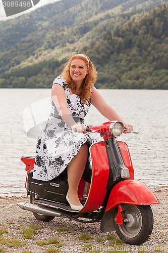 Image of Obese redhead beauty on a red scooter
