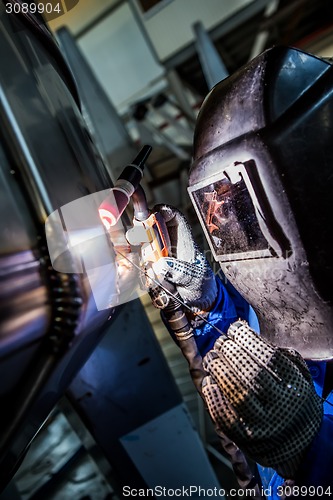 Image of Man welding with reflection of sparks on visor. Hard job. 