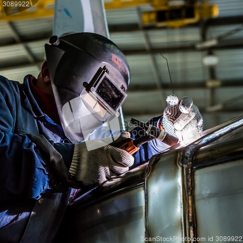 Image of Man welding with reflection of sparks on visor. Hard job. 