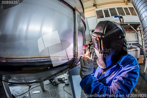 Image of Man welding with reflection of sparks on visor. Hard job. 