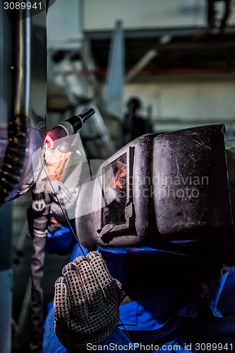 Image of Man welding with reflection of sparks on visor. Hard job. 