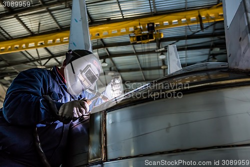 Image of Man welding with reflection of sparks on visor. Hard job. 