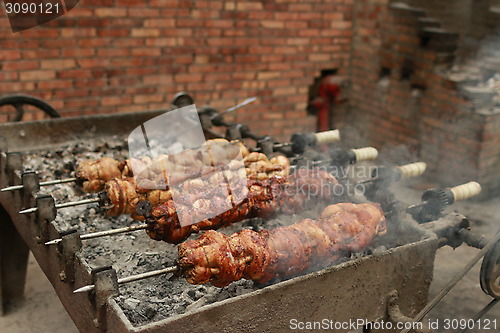 Image of Chickens and Quails getting cooked on huge outdoor Charcoal grill 