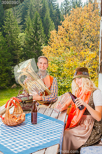 Image of Young couple in traditional Bavarian costume at the party on a summer pasture in the mountains