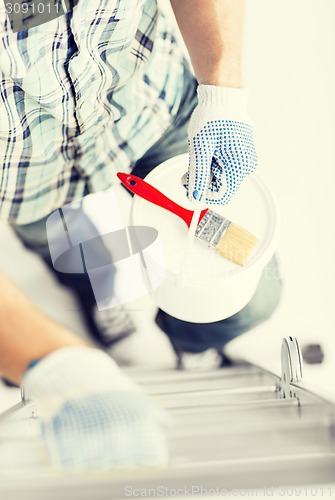 Image of man with paintbrush, pot and ladder