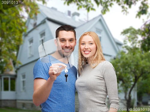 Image of smiling couple showing key over house background