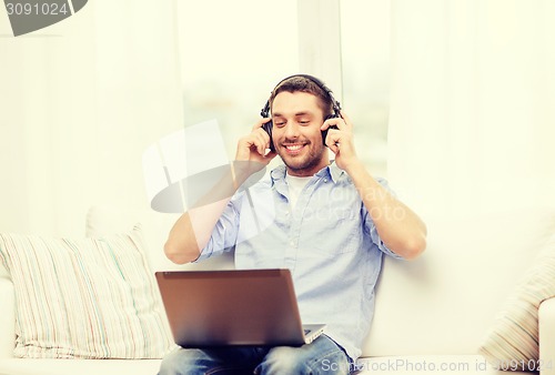 Image of smiling man with laptop and headphones at home