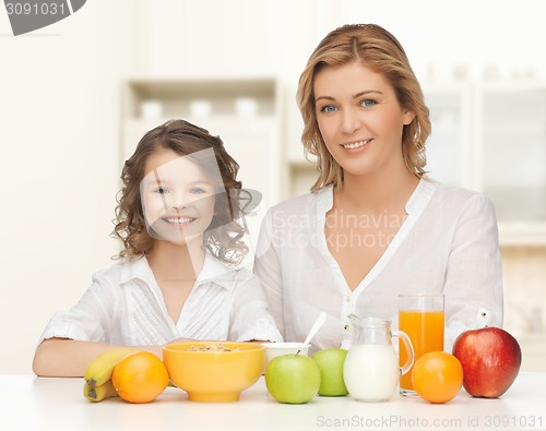 Image of happy mother and daughter eating breakfast