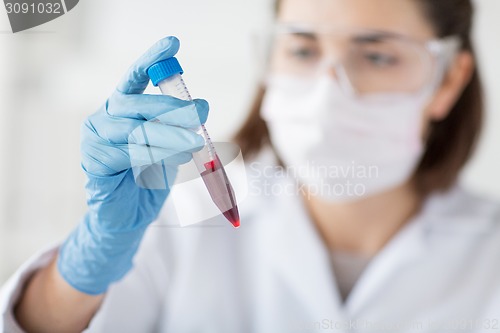 Image of close up of scientist with tube making test in lab