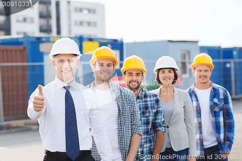 Image of group of smiling builders in hardhats outdoors