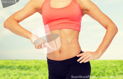 Image of close up of woman pointing finger at her six pack