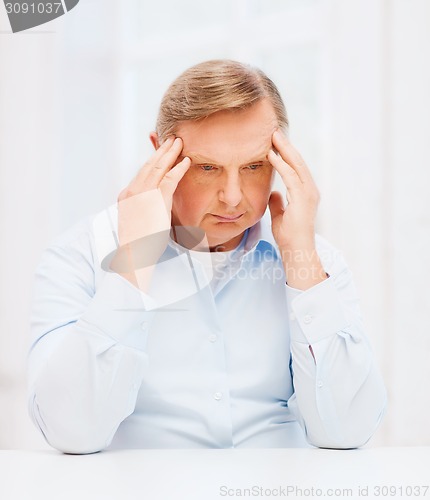 Image of stressed old man holding head at home