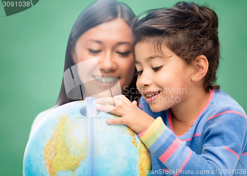 Image of happy teacher and little school girl with globe