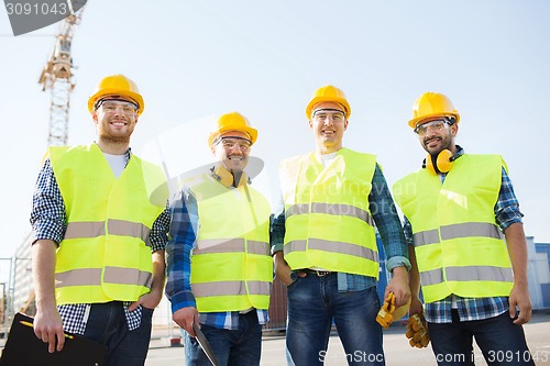 Image of group of smiling builders with tablet pc outdoors