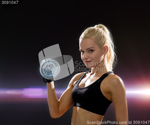 Image of young sporty woman with heavy steel dumbbell