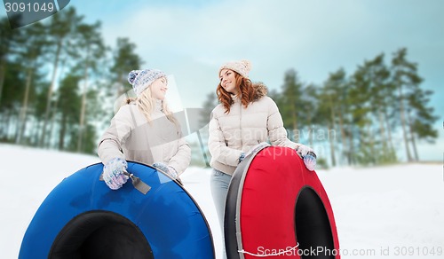 Image of happy girl friends with snow tubes outdoors