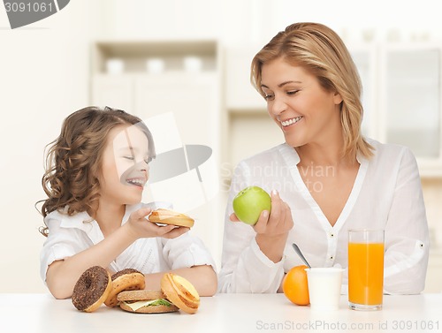 Image of happy mother and daughter eating breakfast