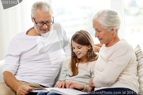 Image of smiling family with book at home