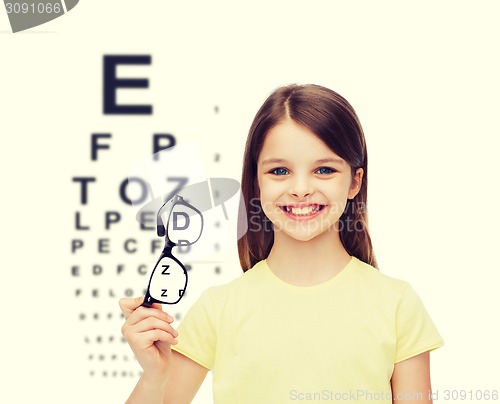 Image of smiling cute little girl holding black eyeglasses