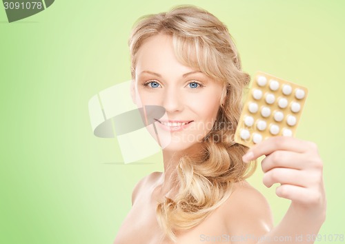 Image of happy young woman holding package of pills