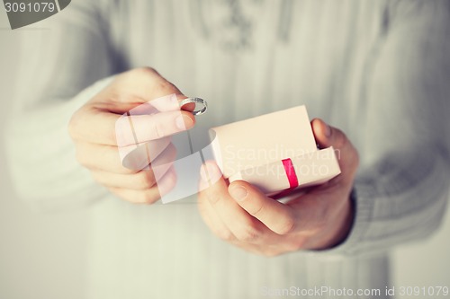 Image of man holding wedding ring and gift box