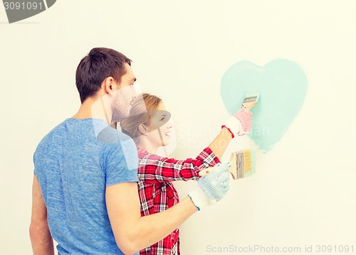 Image of smiling couple painting small heart on wall