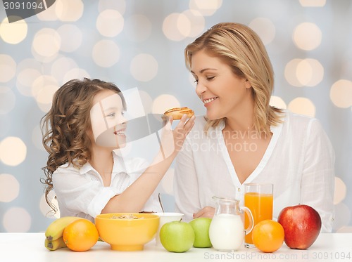 Image of happy mother and daughter eating breakfast