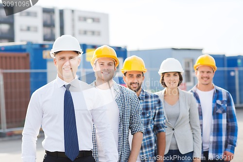 Image of group of smiling builders in hardhats outdoors