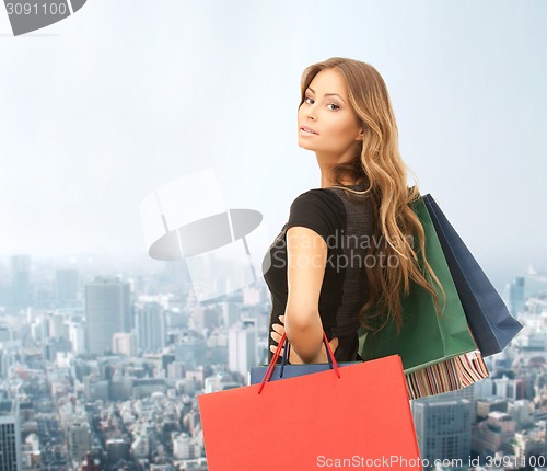 Image of young happy woman with shopping bags over city