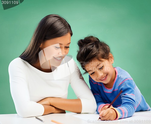 Image of happy teacher and little school girl drawing