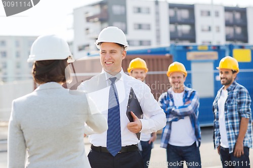 Image of group of smiling builders in hardhats outdoors