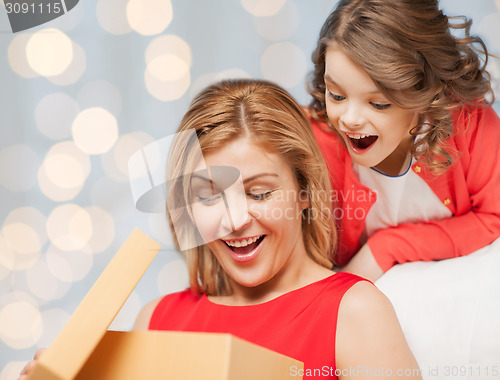 Image of happy mother and daughter opening gift box