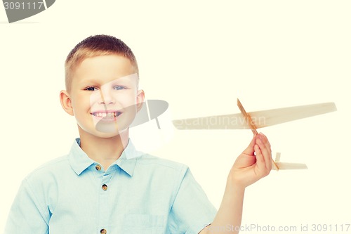 Image of smiling little boy holding a wooden airplane model