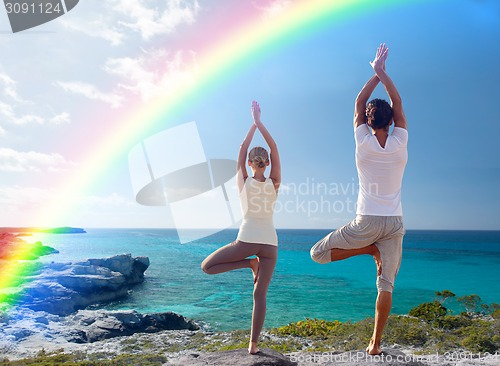 Image of young man making yoga exercises on summer beach