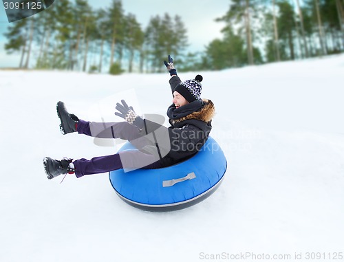 Image of happy young man sliding down on snow tube