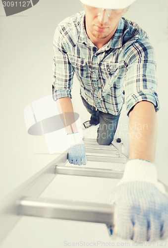 Image of man in helmet and gloves climbing ladder