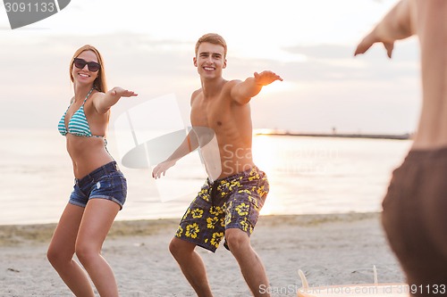 Image of smiling friends in sunglasses with surfs on beach