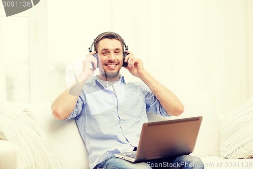 Image of smiling man with laptop and headphones at home