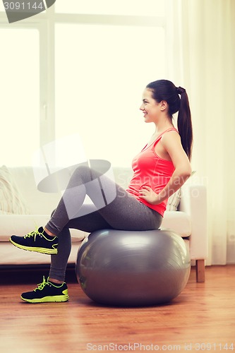 Image of smiling redhead girl exercising with fitness ball