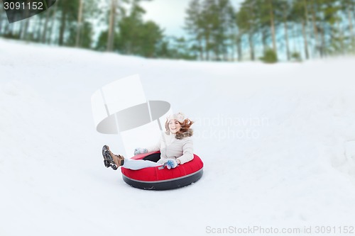 Image of happy teenage girl sliding down on snow tube