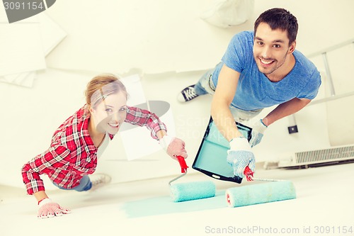 Image of smiling couple painting wall at home