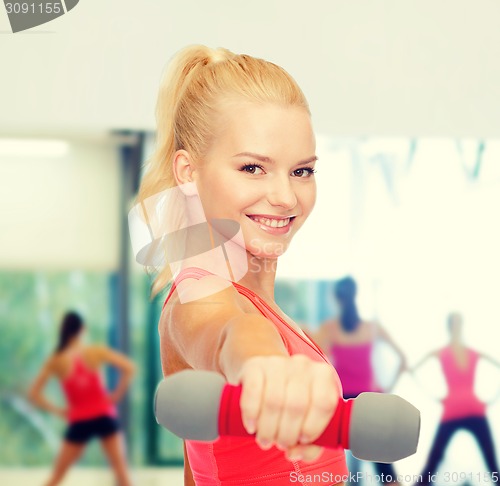 Image of smiling beautiful sporty woman with dumbbell