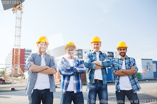 Image of group of smiling builders in hardhats outdoors