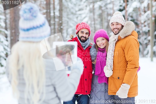 Image of smiling friends with tablet pc in winter forest