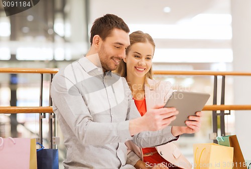 Image of couple with tablet pc and shopping bags in mall