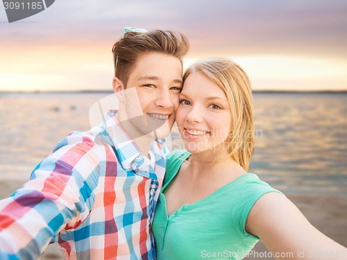 Image of smiling couple with smartphone on summer beach